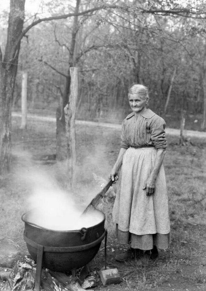 Mujer mayor cocinando al aire libre en un caldero antiguo, imagen inquietante con historia oculta.