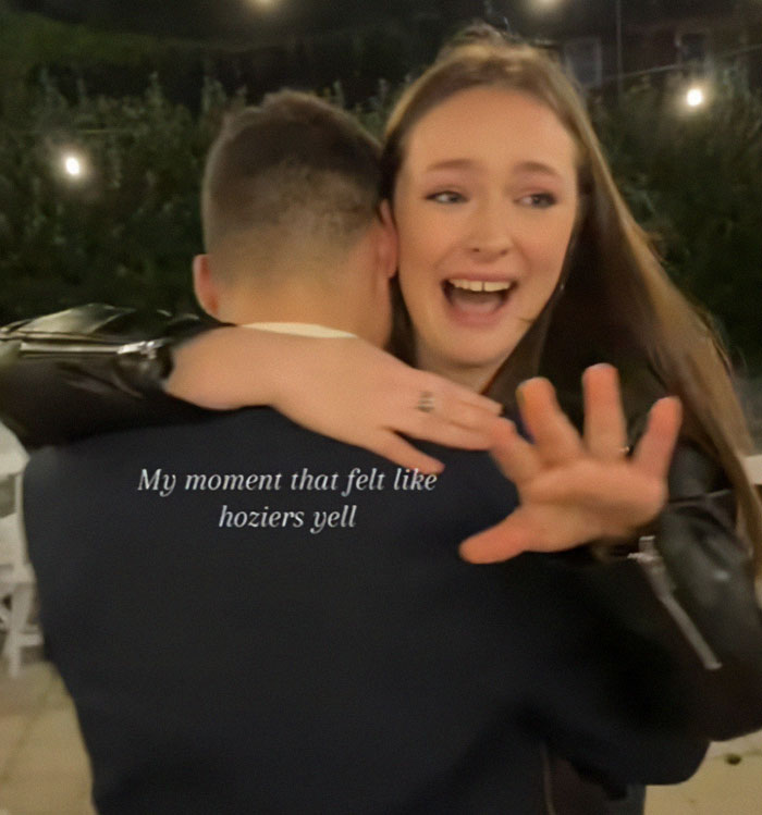 Engaged couple embraces at a wedding, woman reacts excitedly to surprise proposal.