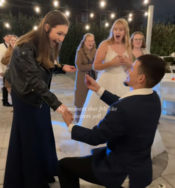 Man proposing to woman at a wedding; others in background appear surprised, enhancing the wedding proposal scene.
