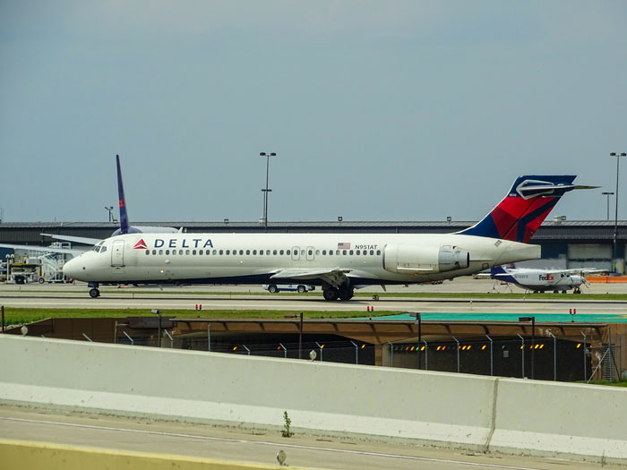 Delta Air Lines plane taxiing on runway at airport, with terminal in background, related to travel seating conflicts.