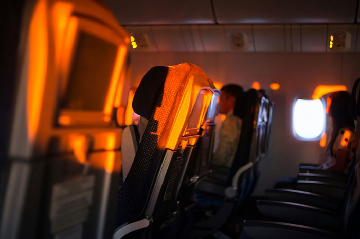 Airplane seats with sunlight streaming through a window, highlighting the seating arrangement.