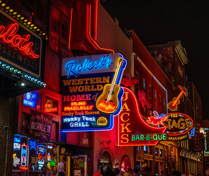 Neon signs of touristy bars and restaurants at night, showcasing vibrant city nightlife.