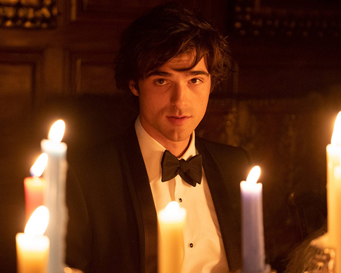 A person in formal attire surrounded by candles, creating a dramatic ambiance related to Wuthering Heights.