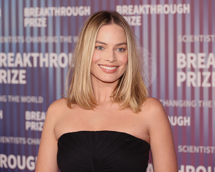 I don&rsquo;t know who this is, but they are at an event with a "Breakthrough Prize" backdrop wearing a strapless black dress.