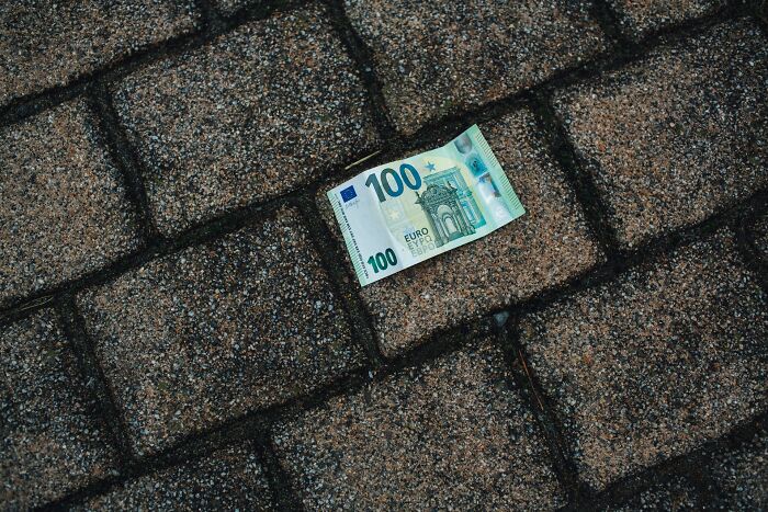 A 100 euro banknote lying on cobblestones, symbolizing winning an eating competition for easy money.