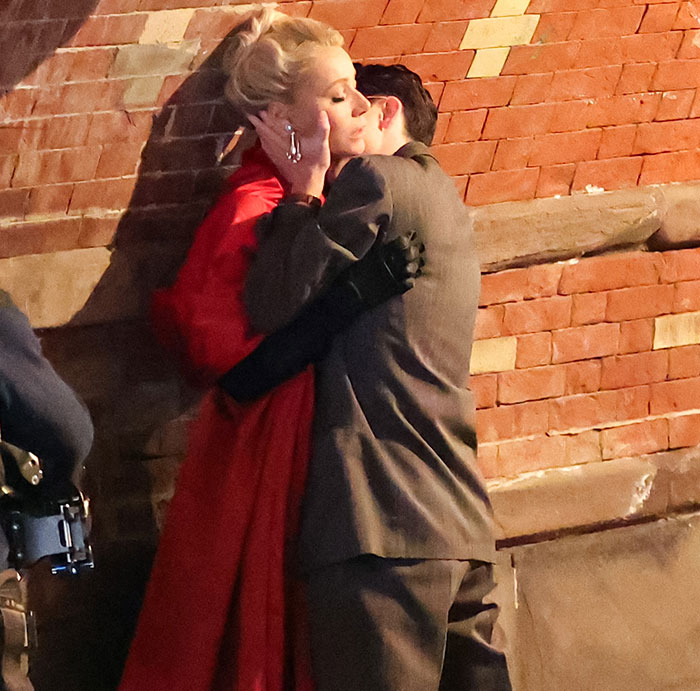 Actors embrace in a passionate scene on a brick wall, reflecting the dynamics of intimacy coordination in film production.