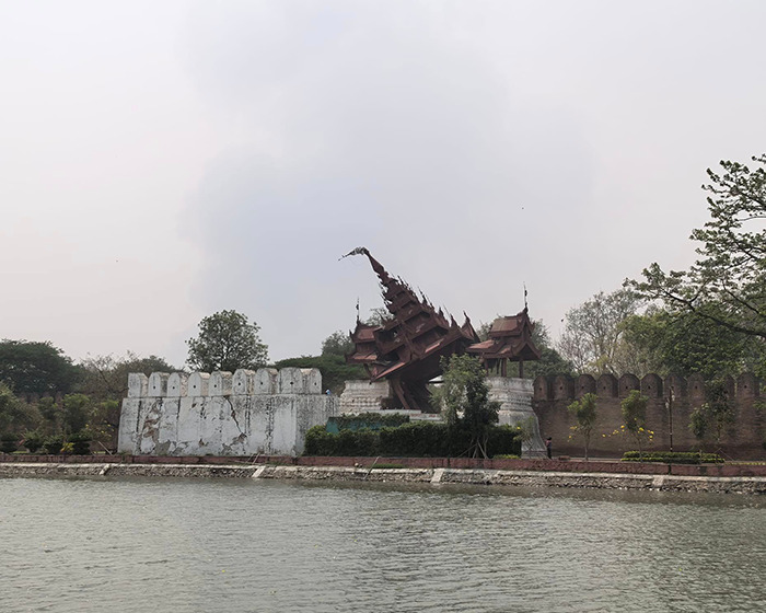 Damaged structure after Myanmar's massive earthquake, leaning precariously amidst surrounding trees and walls.