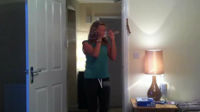 Person surprised in doorway during harmless April Fools' prank, covering face with hands.