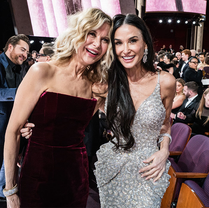 Two women smiling and posing together in elegant dresses during Oscars 2025.