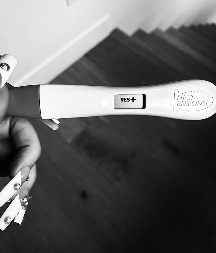 Positive pregnancy test held by a person, suggesting a celestial seed announcement.