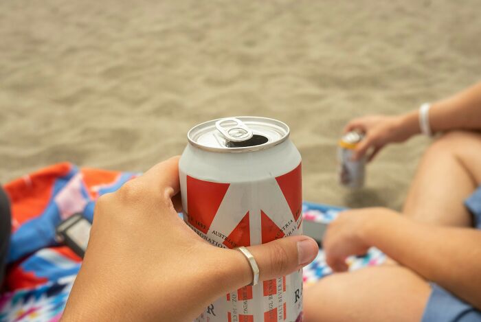 People holding canned drinks at the beach, discussing things not invented already.