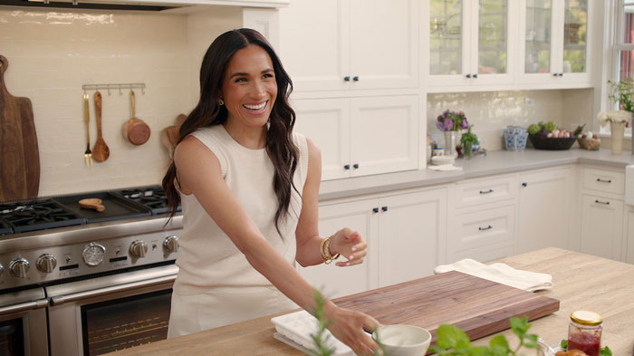 Woman in a bright kitchen setting, smiling and reaching for a bowl. Woman in a bright kitchen setting, smiling and reaching for a bowl.
