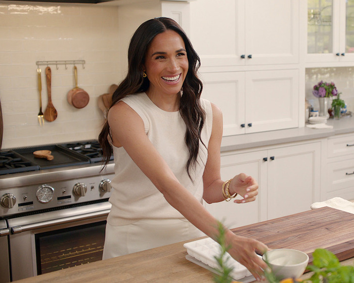 Meghan Markle smiling in a kitchen. Meghan Markle smiling in a kitchen.