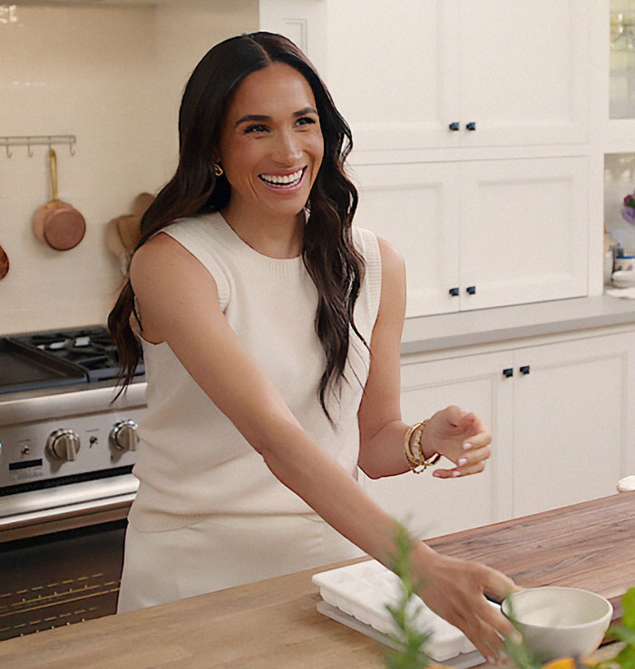 Smiling woman in a stylish kitchen, engaging in casual conversation.