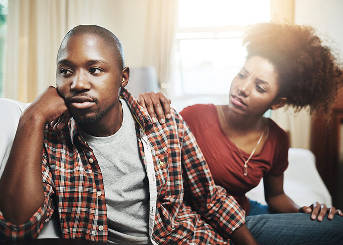 A thoughtful man and concerned woman in discussion, raising questions about men in a sunlit room.