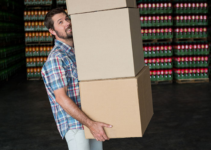 Man carrying large boxes in a warehouse, showcasing questions about men and physical strength.
