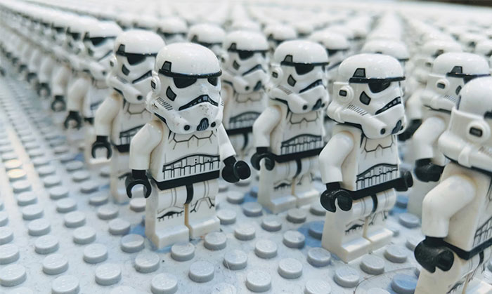 Figuras de stormtroopers LEGO en formación sobre superficie blanca.
