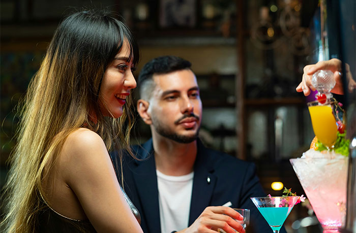 Hombres y mujeres conversando en un bar, con cócteles y una atmósfera relajada.