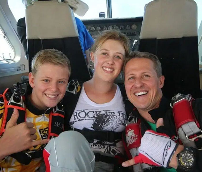 Family moment with Michael Schumacher, smiling in a plane, wearing parachute gear.