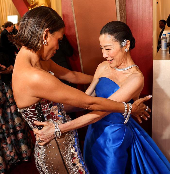 Two women embrace in stylish gowns, sharing a moment at the Oscars 2025.