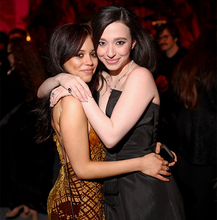 Two individuals embracing at Oscars 2025 event, one in a gold dress and the other in black, highlighting behind-the-scenes moments.