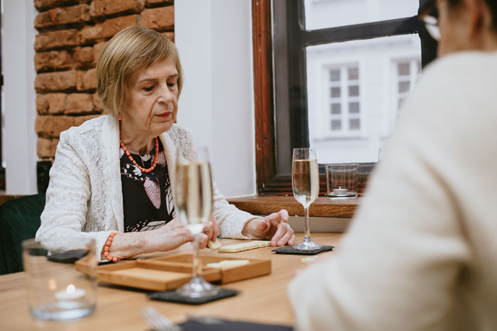 Elderly woman seated at a table with champagne, suggestive of a missing wallet scenario. Elderly woman seated at a table with champagne, suggestive of a missing wallet scenario.