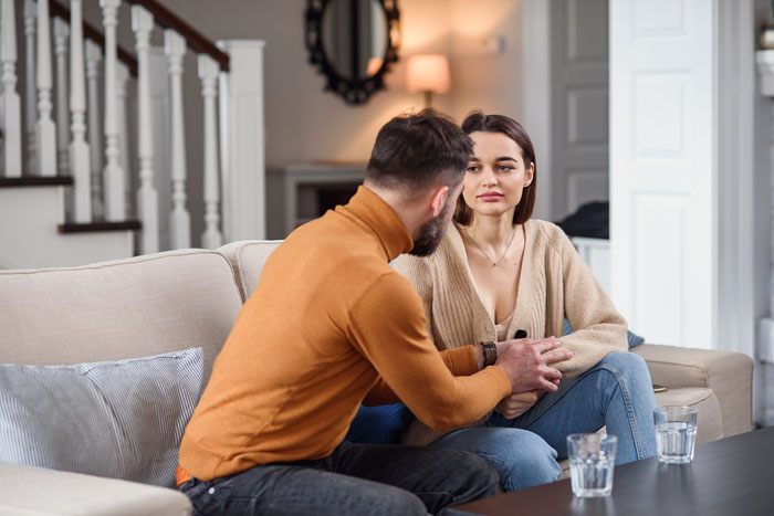 A couple discussing family heirloom wedding ring dispute in a modern living room. A couple discussing family heirloom wedding ring dispute in a modern living room.