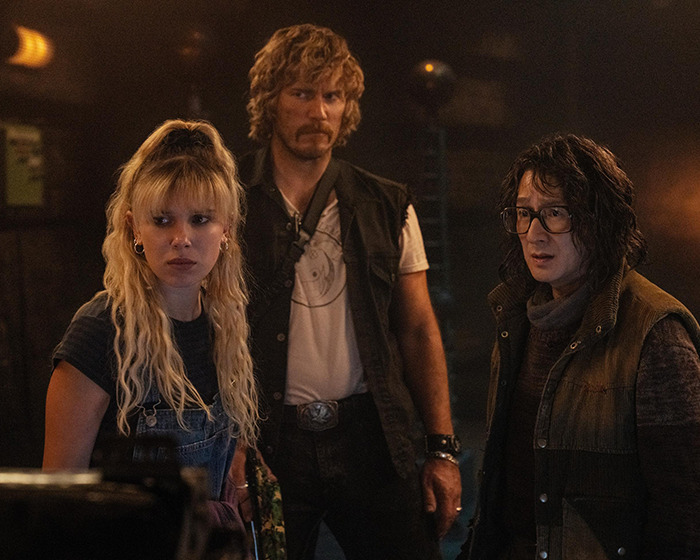 Three people in a dimly lit room with intense expressions.