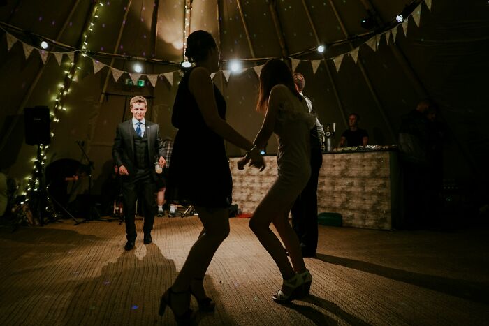 Guests dancing at a dimly lit wedding reception with a band, showcasing a moment weddings went wrong.