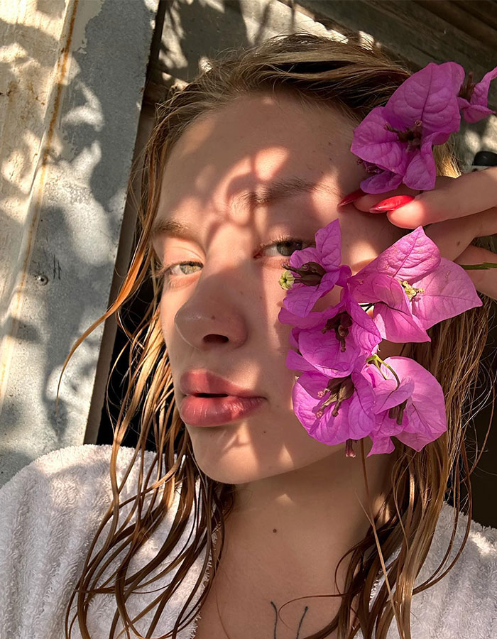 Model with wet hair, wrapped in a towel, holding pink flowers, related to assault case investigation and "Porta Potty" parties.