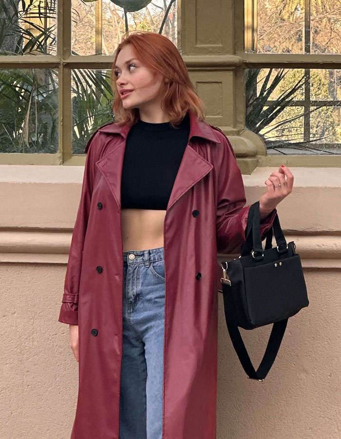 Red-haired woman in a maroon trench coat holding a handbag, related to model&rsquo;s assault case and possible trafficking.