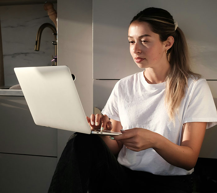 Person in a white shirt using a laptop, highlighting modern conveniences in everyday life.