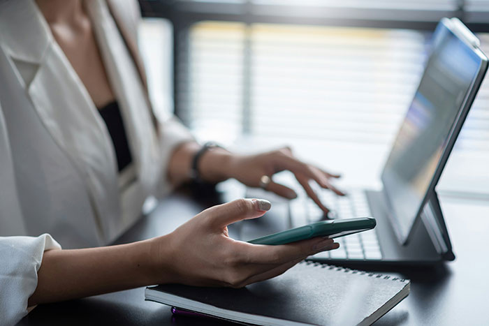 Person multitasking with smartphone and laptop, illustrating modern conveniences in daily life.
