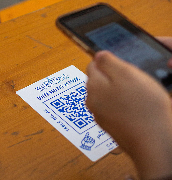 Person scanning QR code at a restaurant table, exemplifying modern conveniences.
