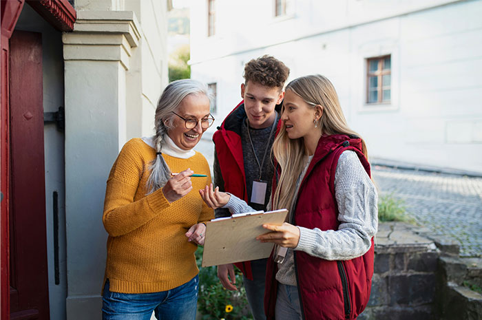 Three people in casual attire smiling and discussing in an outdoor setting, one holding a clipboard, related to industry insights.