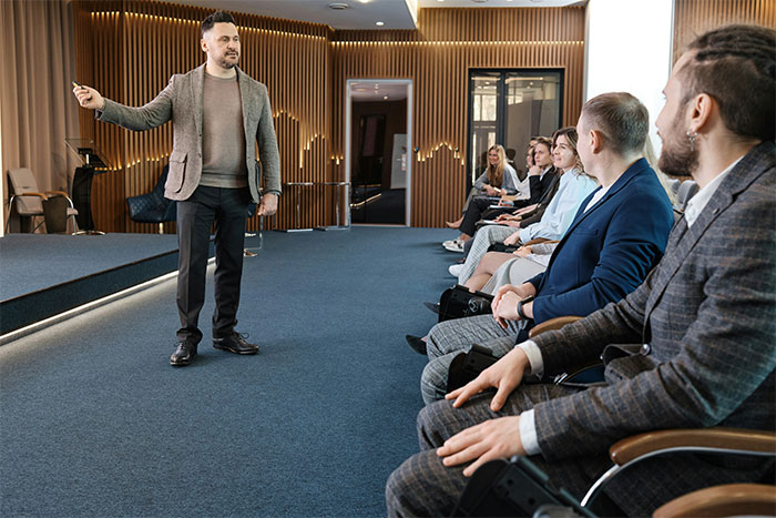 Man giving a presentation to a seated audience in a modern room, illustrating industry insights.