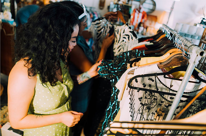 Women browsing clothes in a vintage store, exploring the fashion industry.