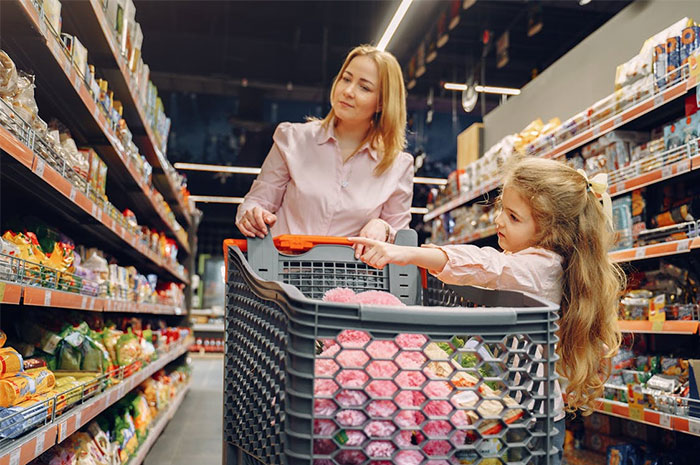 Mother and daughter shopping in a grocery store aisle, highlighting industry pricing perceptions.