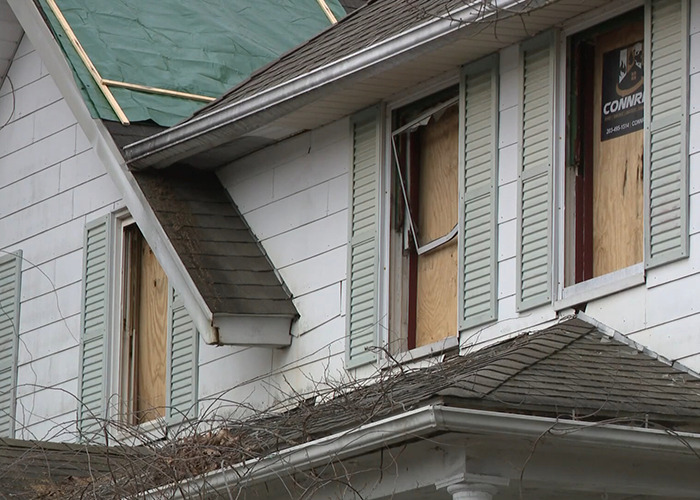 Damaged house with boarded windows linked to imprisoned stepson case and escape fire.
