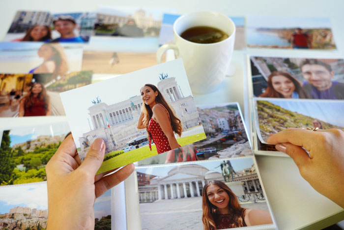 Person holding photos with a cup of tea in the background, depicting memories related to husband's late wife.