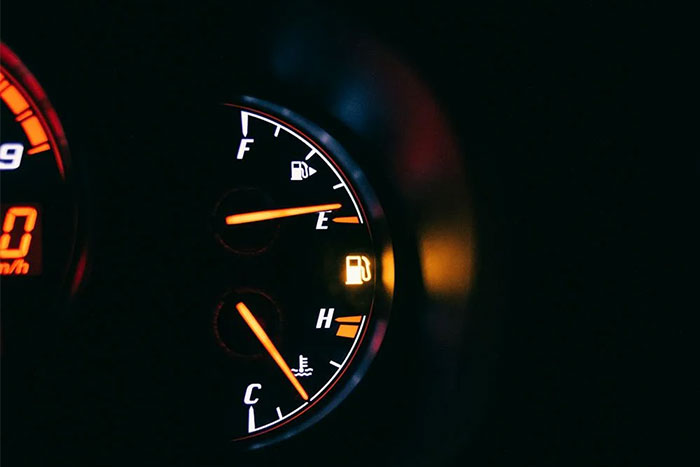 Fuel gauge showing empty with illuminated warning light, capturing a coincidental moment of near-empty gas tank.