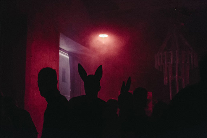 Silhouettes in a red-lit room, evoking mysterious coincidences.