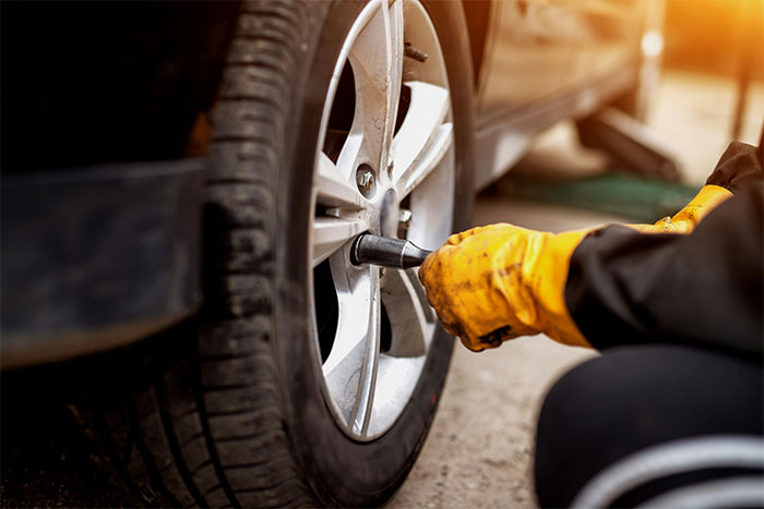 Mechanic wearing gloves fixing car tire, showing an unforgettable coincidence in auto repair.
