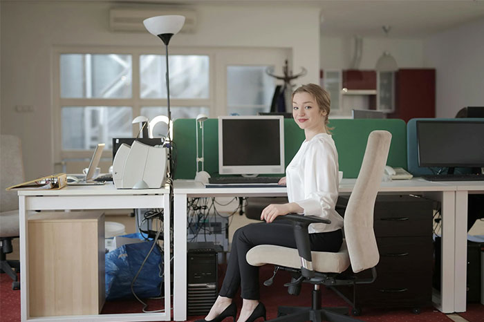 Woman sitting in an office, wearing a white blouse, symbolizing unforgettable coincidences in a work environment.