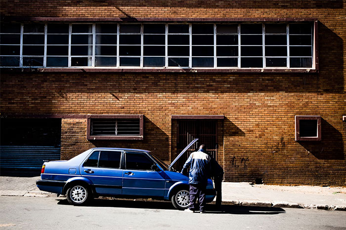 Man inspecting a blue car on a street, illustrating a memorable coincidence event.