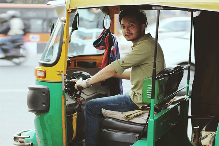 Man driving a green auto rickshaw on a busy street, illustrating a crazy coincidence story.