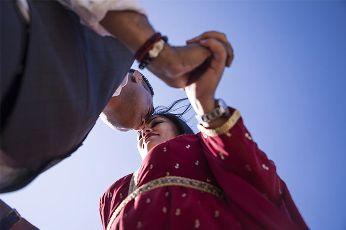 Couple holding hands and kissing under a blue sky, experiencing an unforgettable coincidence moment.