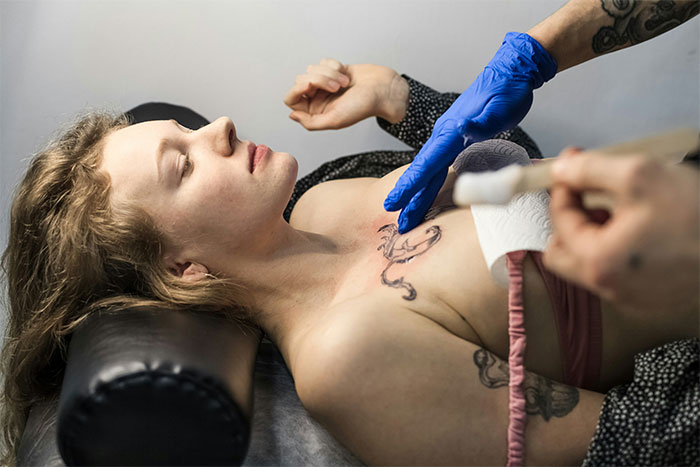 Woman getting a tattoo on her chest, showing a unique bridesmaid request.