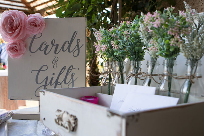 Cards and gifts table at a wedding, featuring pink roses and rustic decor, related to bridesmaid requests.
