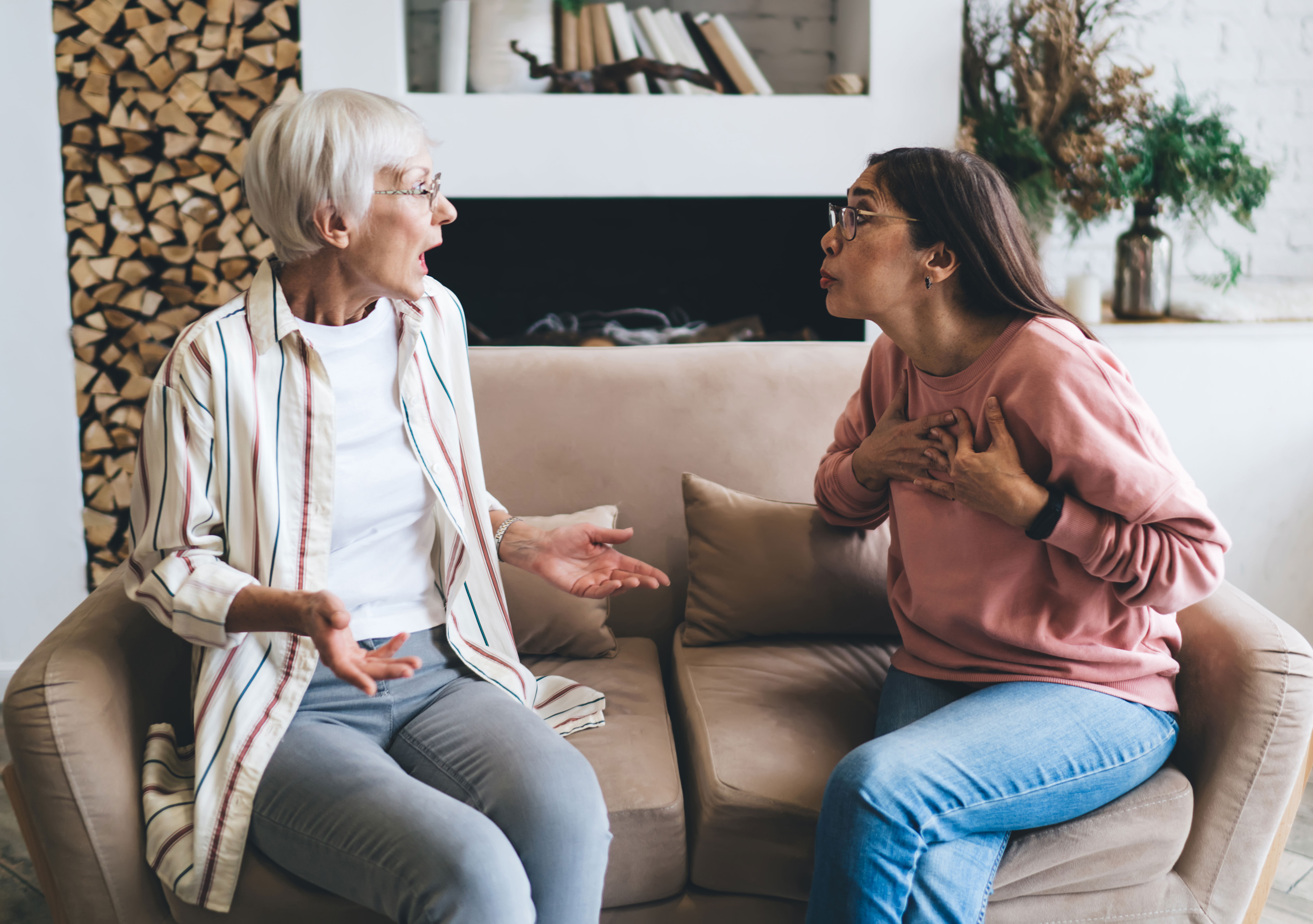Two women having an intense conversation on a sofa, highlighting transformation and personal growth through living well.